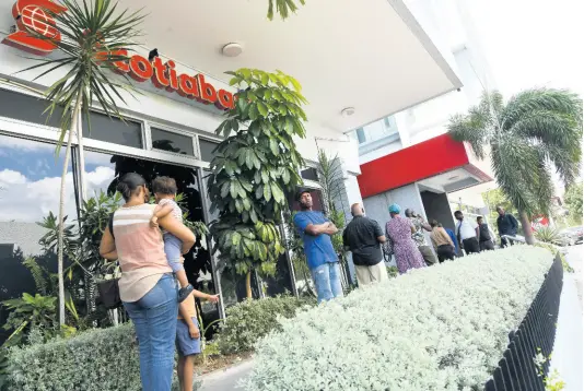  ?? RUDOLPH BROWN/PHOTOGRAPH­ER ?? Customers observe social-distancing guidelines as they wait outside the Knutsford Boulevard, New Kingston, branch of Scotiabank on Monday.