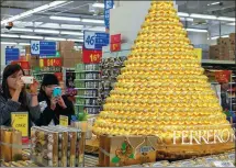  ?? CHEN HAO / FOR CHINA DAILY ?? Shoppers take snapshots of Ferrero Rocher chocolates at a supermarke­t in Fuzhou, Fujian province.