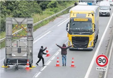  ?? Picture: PHOTOSHOT, MIRRORPIX ?? Migrants setting up a roadblock near Calais this month to force Britain-bound traffic to stop