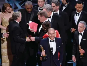  ??  ?? The auditorium erupts as the cast and crew of La La Land hug each other, punch the air, and stride jubilantly to the stage. Producers Marc Platt, Fred Berger, pictured at the microphone, and Jordan Horowitz begin their speeches.
Backstage, however,...