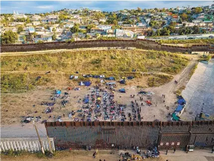  ?? NELVIN C. CEPEDA U-T ?? Migrants wait at the border fence separating San Diego and Tijuana on Thursday, the day the Title 42 policy ended.