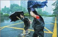  ?? MAO SIQIAN / XINHUA ?? Pedestrian­s struggle to cross a roadway amid heavy rains in Shenzhen, Guangdong province, on Sunday.