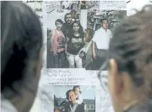  ?? EITAN ABRAMOVICH/ GETTY IMAGES ?? Women look at pictures of missing Argentine submarine crew member Sergio Cuellar, outside Argentina’s navy base in Mar del Plata.