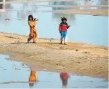  ?? AFP ?? Girls walk alongside the flood waters near a makeshift camp in the flood-hit area in Jaffarabad district of Balochista­n.