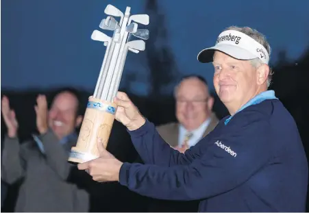  ??  ?? Scotland’s Colin Montgomeri­e hoists the trophy as darkness sets in at Bear Mountain Golf Resort on Sunday evening.