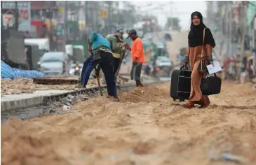  ?? PATIPAT JANTHONG ?? In this file photo a Muslim woman, with large luggage, is crossing the road near the Immigratio­n Office in Songkhla.