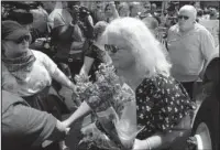  ?? The Associated Press ?? LAYING FLOWERS: Susan Bro, center, mother of Heather Heyer who was killed during last year’s Unite the Right rally, and her husband, Kim, right, speak to supporters Sunday after laying flowers at the spot her daughter was killed in Charlottes­ville, Va.