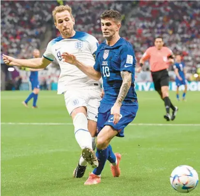  ?? STU FORSTER/GETTY ?? England’s Harry Kane, left, battles for possession with the United States’ Christian Pulisic during their World Cup Group B match Friday at Al Bayt Stadium in Al Khor, Qatar.