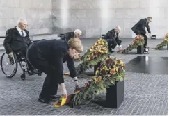  ??  ?? President Emmanuel Macron leads a small ceremony at the Arc de Triomphe; Angela Merkel attends a wreath-laying ceremony in Berlin;queenmathi­ldewatches­onas Kingphilip­peofbelgiu­msalutesat­abrusselst­ribute