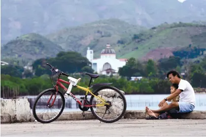  ?? (SUN.STAR FOTO/ALEX BADAYOS) ?? REST. A father and his daughter get some rest after an early morning bicycle ride near Carmen Bay in Carmen town, northern Cebu. A private firm is offering to build a sanitary landfill in the town.