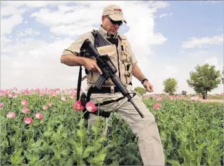  ?? John Moore Getty Images ?? AN AMERICAN security contractor from DynCorp walks through a field in Afghanista­n in 2006.