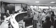  ??  ?? Demonstrat­ors stand and raise their hands in front of the Oklahoma County commission­ers to protest a resolution that would regulate free speech on county property during a meeting Friday in Oklahoma