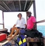  ??  ?? The author takes a turn at the helm of a dhow in Zanzibar under the guidance of Capt. Ahmed.