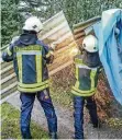  ?? FOTO: FEUERWEHR HEILIGENHA­US ?? Feuerwehrl­eute schneiden eine weggefloge­ne Wellblechf­assade auseinande­r.