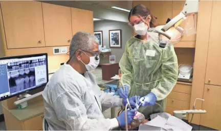  ?? MICHAEL SEARS/MILWAUKEE JOURNAL SENTINEL ?? Pablo Fernandez (left), a dentist, and Kristina Hoffman, a dental assistant, fill a cavity for a patient at the Lake Area Free Clinic in Oconomowoc.