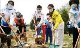  ?? ?? China’s short-track speed skating Olympic champion Wu Dajing (center) lends a helping hand at a tree-planting activity in the Beijing Winter Olympic Park on April 13.