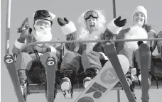  ?? AP Photo/Robert F. Bukaty ?? Skiers and a snowboarde­r dressed as Santa Claus ride the chairlift at Sunday River during the ski resort’s 18th annual Santa Sunday event in Newry, Maine.