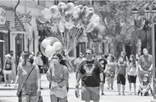  ?? JOHN RAOUX/ASSOCIATED PRESS ?? Guests required to wear masks because of the coronaviru­s stroll through the Disney Springs shopping, dining and entertainm­ent complex June 16 in Lake Buena Vista, Fla. Disney’s Magic Kingdom and Animal Kingdom in Florida will reopen Saturday.