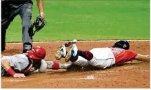  ?? TONY DEJAK / AP ?? Cleveland’s Oscar Mercado slides safely into home plate as Cincinnati’s Tucker Barnhart is late with the tag in the bottom of the fifth inning Wednesday. A second loss in a row to the Indians left the Reds five games back of the Cubs in the NL Central.