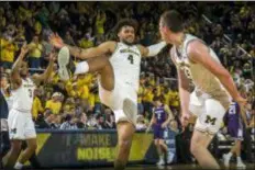  ?? TONY DING — THE ASSOCIATED PRESS ?? Michigan guard Zavier Simpson and forward Isaiah Livers celebrate with center Jon Teske, right, after Teske made consecutiv­e three-point baskets in the first half of Saturday’s game against Northweste­rn at Crisler Center in Ann Arbor, Mich.