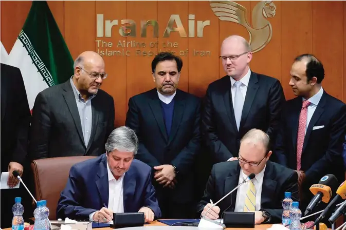  ?? —AFP ?? TEHRAN: Farhad Parvaresh (left), Chairman and Managing Director of Iran Air, and Fletcher Barkdull, Boeing regional director, sign an agreement in the presence of Abbas Ahmad Akhoundi (center), Minister of Roads and Urban Developmen­t, in the capital...