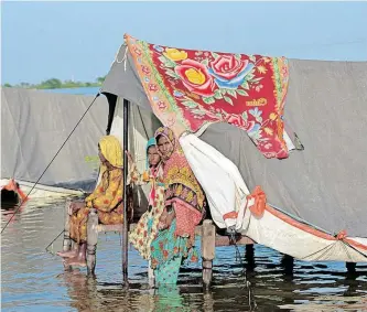  ?? ?? FLOOD victims sit on a bed with their belongings as floodwater rises, after rains during the monsoon season in Sohbatpur, Pakistan this week. Melting glaciers are also contributi­ng to further flooding in parts of the country. | REUTERS