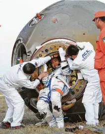  ??  ?? Chinese astronaut Zhai Zhigang is helped out of the spacecraft after his country’s first-ever spacewalk.