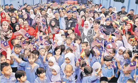  ??  ?? Fifth Region Marine Police (PPM W5) Commander ACP Salehuddin Mat Zaman, seen here holding a boy who is waving Jalur Gemilang, joins Community Developmen­t Department (Kemas) pre-schoolers and their teachers in a group photo during the ‘Moh Ngeteh...