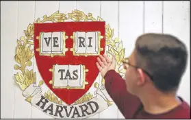  ??  ?? Cross Keys senior Yusuf Azizi points out a Harvard crest his mother Nabila Azizi made as part of decoration­s in the family home to celebrate his graduation. Yusuf is headed to Harvard University.