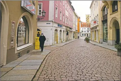  ??  ?? A man walks down a street near the market place in the nearly deserted old city of Meissen. Meissen County leads Germany’s covid league tables, with a current infection rate three times the national average. The state of Saxony, where Meissen is located, includes some of the worst-hit counties in Germany.