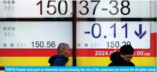  ?? – AFP ?? TOKYO: People walk past an electronic board showing the rate of the Japanese yen versus the US dollar along a street in Tokyo.