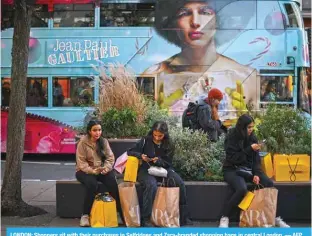  ?? — AFP ?? LONDON: Shoppers sit with their purchases in Selfridges and Zara-branded shopping bags in central London.