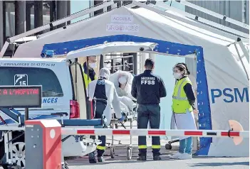  ?? — AFP photo ?? Doctors tend to a patient arriving on a wheelchair at the reception of the Emergency Room, set up in a tent, in a courtyard of the Henri Mondor Hospital in Creteil, near Paris on the fourteenth day of a lockdown in France.