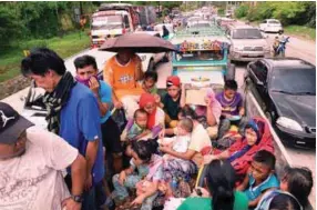  ??  ?? Residents fleeing from Marawi are cramped on a truck as they traverse a traffic gridlock near a police checkpoint at the entrance to the city of Iligan yesterday.