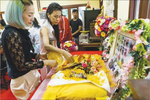  ?? AMANDA MUSTARD / THE NEW YORK TIMES ?? The owners of a dog named Kaew, or Wonton, sprinkle f lower petals onto the dog’s body at a Buddhist temple in Bangkok. Thailand’s capital, with little green space and deadly reptiles, is not ideal for pets, but owners spoil their dogs and cats in life...