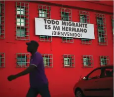  ?? — Reuters ?? An Haitian immigrant walks past a banner that reads “All immigrant is my brother. Welcome!”, outside a church in Santiago, Chile, in this file photo taken on December 18, 2016.