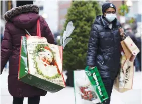  ?? AP PHOTO/MICHAEL DWYER ?? People carry shopping bags Saturday at Downtown Crossing in Boston.