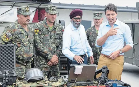  ?? ROMAN KOKSAROV THE ASSOCIATED PRESS ?? Prime Minister Justin Trudeau, right, and Defence Minister Harjit Singh Sajjan inspect equipment at the Adazi military base in Latvia on Tuesday.