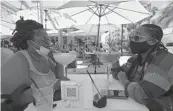  ?? WILFREDO LEE/AP ?? Anita Anderson, left, of Grand Rapids, Mich., and her niece Tawnya Heggins of Houston, chat as they dine outside a restaurant on Miami Beach on Friday. Florida banned alcohol consumptio­n at its bars Friday as its daily confirmed coronaviru­s cases neared 9,000, a new record that is almost double the previous mark set just two days ago.