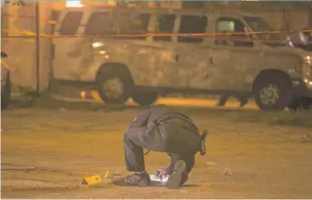  ??  ?? A Chicago Police evidence technician examines the scene of a fatal shooting in July.