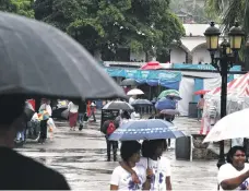  ?? ?? Los que llegaron a la Feria, se protegiero­n con paraguas.