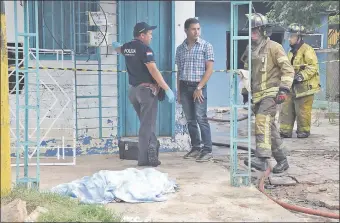  ??  ?? Policías y bomberos voluntario­s observan el cuerpo de la mujer, que quedó tendida en la vereda de la casa.