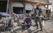  ?? IVOR PRICKETT / THE NEW YORK TIMES ?? U.S.-backed Syrian Democratic Forces fighters take a breather Feb. 2 near Baghouz, the last town in Syria held by the Islamic State. A stream of families and fighters, many hungry or injured, are fleeing the Islamic State’s last sliver of land.