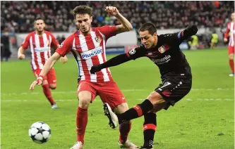  ?? —AP ?? LEVERKUSEN: Leverkusen’s Javier Hernandez, right, shoots on the goal past Atletico’s Saul Niguez during the Champions League round of 16 first leg soccer match between Bayer Leverkusen and Atletico Madrid in Leverkusen, Germany, yesterday.