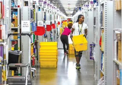  ?? STAFF PHOTO BY DOUG STRICKLAND ?? Workers fill totes with merchandis­e in the pick mod area of the Amazon Fulfillmen­t Center in Enterprise South Industrial Park in 2017 in Chattanoog­a. The e-commerce giant said that it planned to spend $700 million to retrain a third of its workers in the U.S.