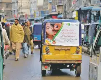  ?? MUHAMMAD SAJJAD/ASSOCIATED PRESS ?? An auto rickshaw with a poster advertisin­g a polio campaign drives through a market in Peshawar, Pakistan. In Pakistan, delivering vaccines can be deadly.