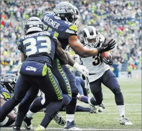  ?? Elaine Thompson ?? The Associated Press Rams running back Todd Gurley, right, runs for a touchdown against Bobby Wagner, Tedric Thompson and the Seahawks’ defense Sunday in Seattle. Gurley rushed for three touchdowns in Los Angeles’ 33-31 victory.