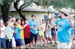  ??  ?? In this July 6, 2015 photo, released by Camp Kiwanis, games instructor John Griffin (right), shouts directions through a megaphone as campers look on at Camp Kiwanis in the Ocala National Forest near Ocala, Florida. Camp Kiwanis will not open this summer for the first time in 72 years due to concerns about spread of the novel coronaviru­s. (AP)
