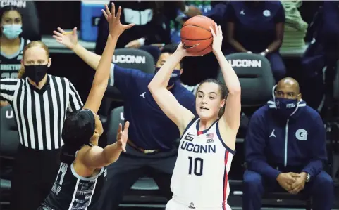  ?? David Butler II / Associated Press ?? UConn’s Nika Muhl (10) looks to pass while defended by Georgetown’s Jillian Archer (14) on Saturday in Storrs.