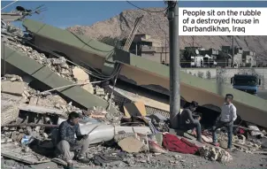  ??  ?? People sit on the rubble of a destroyed house in Darbandikh­an, Iraq